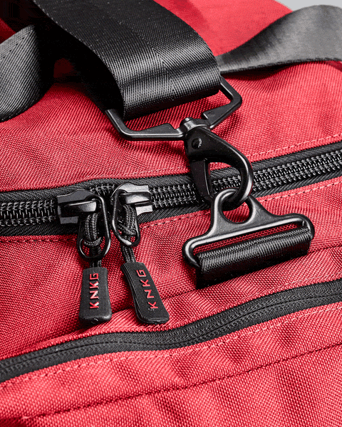Close up of YKK zippers and carbon steel buckles on red PLUS Duffel