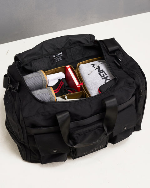 Gym essentials organized inside dividers in large black KNKG PLUS duffel