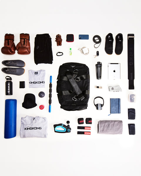 Birds eye view flat lay of gym essentials that fit inside large black KNKG PLUS duffel
