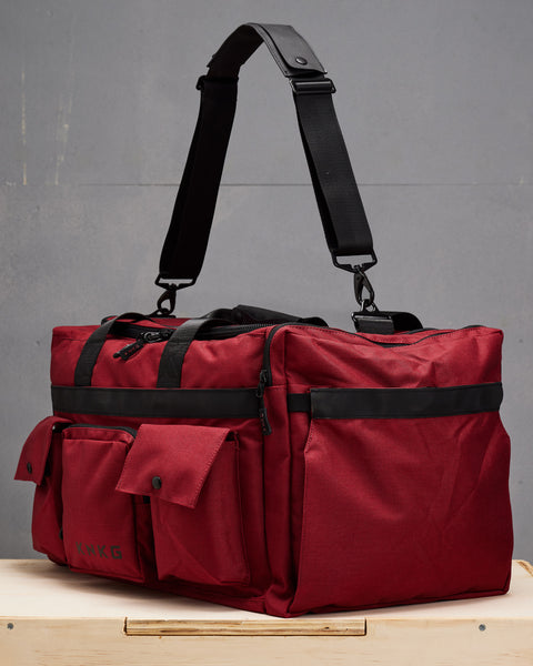 Side profile view of KNKG large red PLUS Duffel