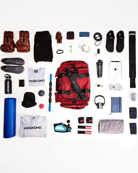 Flat lay of items that can fit inside KNKG large red PLUS Duffel