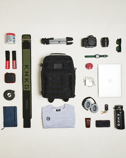 Flat lay of gym gear being packed inside of Small black KNKG CONQUER Backpack