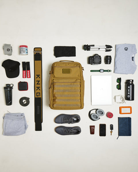 Flat lay of gym gear that fits inside of desert KNKG CONQUER Backpack