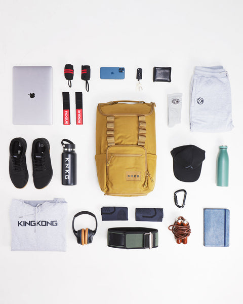 Flat lay of items that fit inside of desert KNKG CORE Backpack