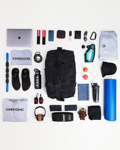 Flat lay of large black KNKG CORE Duffel surrounded by gym gear