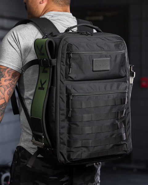 Man wearing large black CONQUER Backpack inside gym