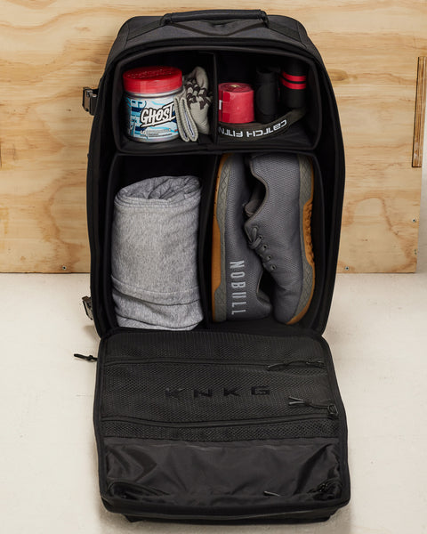 Internal dividers of large black CONQUER Backpack packed with shoes, pre-workout, wrist wraps, workout clothes and fitness accessories