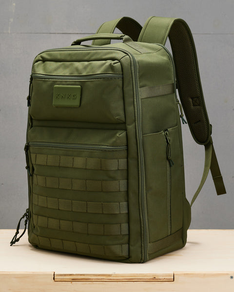 Side view of large green CONQUER Backpack sitting on wooden box