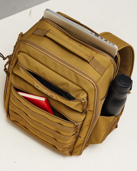 Top view of pockets of Small desert KNKG CONQUER Backpack packed with laptop, drink bottle and notebook