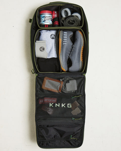 flat lay of  large green CONQUER Backpack internal dividers packed with gym gear