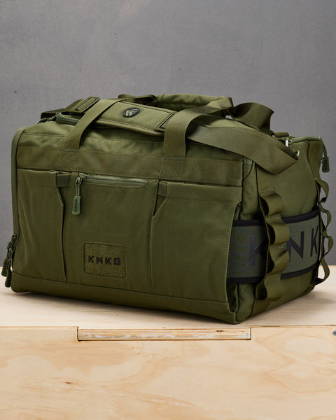 Green CORE Duffel sitting on wooden box with matching green weight lifting belt