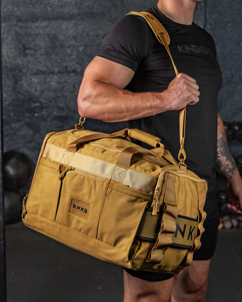 Man wearing desert CORE Duffel over shoulder inside gym