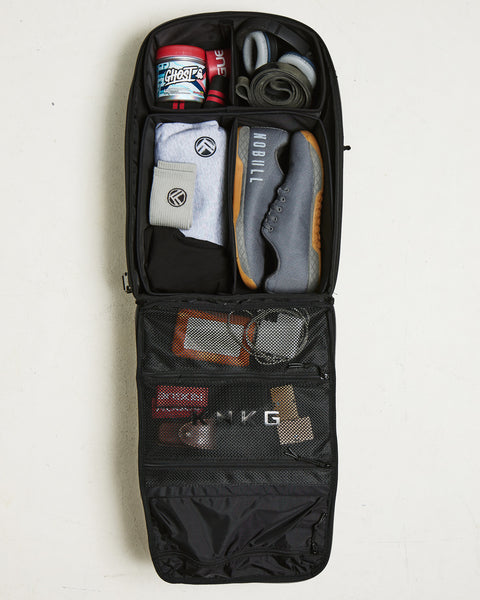Internal dividers of large black CONQUER Backpack packed with gym gear, laying on floor