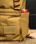 close up of logo and drink bottle pocket of KNKG CORE Mini Backpack in Tan Desert color