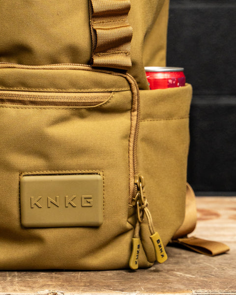 close up of logo and drink bottle pocket of KNKG CORE Mini Backpack in Tan Desert color