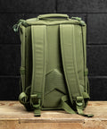 Back view of green mini size KNKG CORE Backpack  on wooden surface inside gym