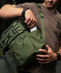 Athlete reaching for pre-workout drink in green mini size KNKG CORE Backpack side pocket