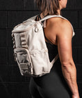 Female Athlete wearing Neutral beige mini size KNKG CORE Backpack 