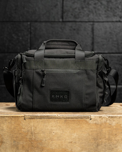 KNKG mini black CORE Duffel sitting on wooden box in gym
