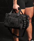 Person holding KNKG mini black CORE Duffel in hand by handle 