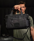 Person holding KNKG mini black CORE Duffel by grab handle