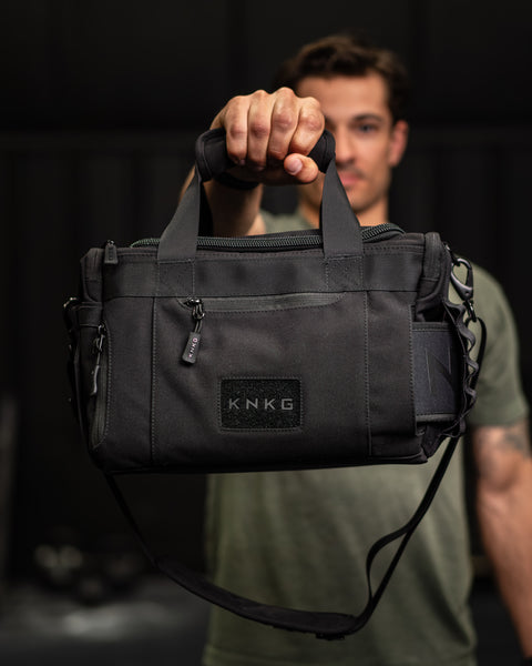 Person holding KNKG mini black CORE Duffel by grab handle