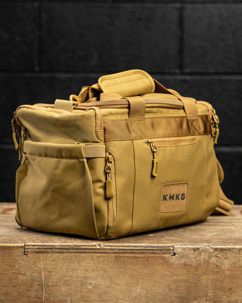 Side view of KNKG desert tan color mini CORE duffel in gym