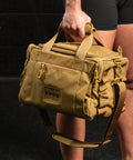Athlete holding KNKG desert tan color mini CORE duffel by handle 
