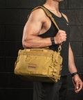 Person wearing KNKG desert tan color mini CORE duffel over shoulder in gym