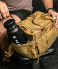 Person packing water bottle in pocket of KNKG desert tan color mini CORE duffel