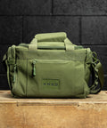 green KNKG mini duffel sitting on wooden box inside gym