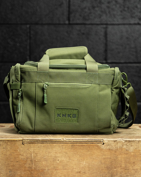green KNKG mini duffel sitting on wooden box inside gym