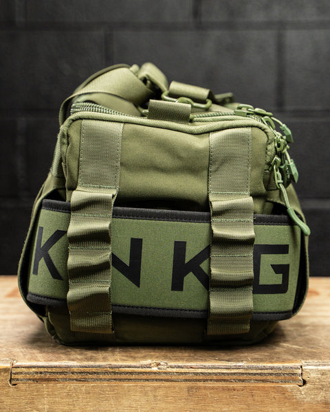 Close up of lifting belt attached to side of green KNKG mini duffel