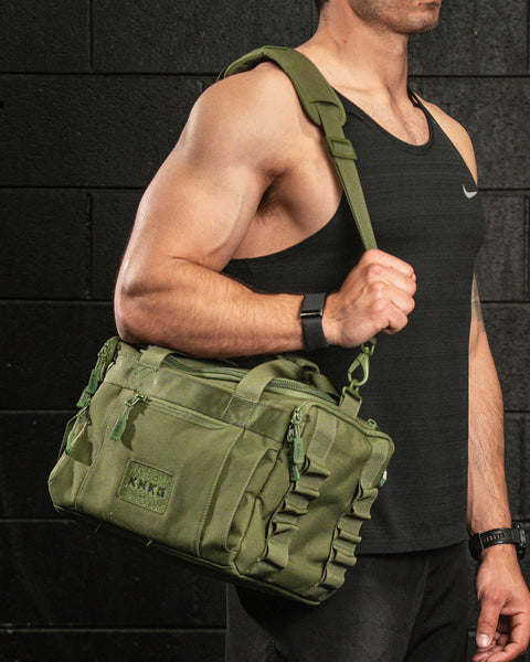 Person wearing green KNKG mini duffel over shoulder inside gym