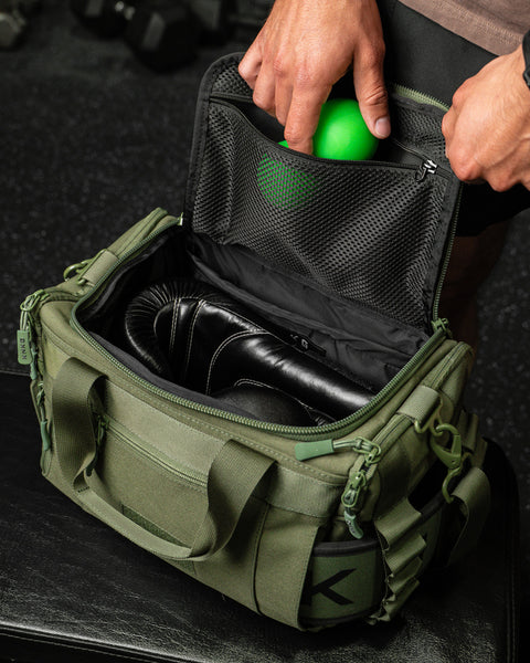 Person packing green KNKG mini duffel with mobility accessories 