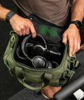 Person packing headphones inside green KNKG mini duffel
