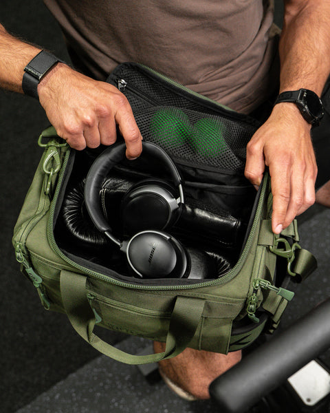 Person packing headphones inside green KNKG mini duffel