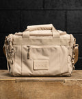 Front view of Neutral beige KNKG mini CORE Duffel sitting on wooden box