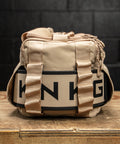 Neutral beige KNKG mini CORE Duffel with matching lifting belt inside side sleeve