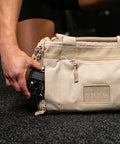 Person reaching for phone inside pocket of Neutral beige KNKG mini CORE Duffel
