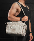Man carrying Neutral beige KNKG mini CORE Duffel over shoulder