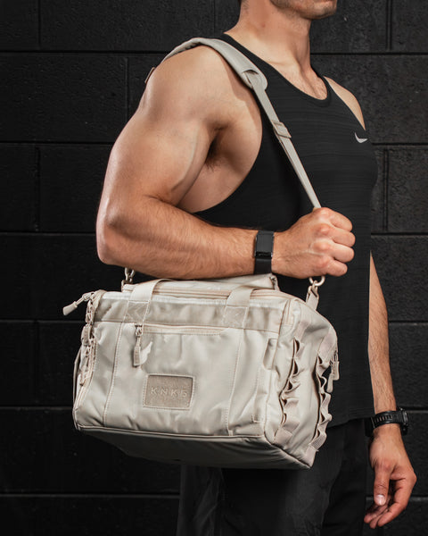 Man carrying Neutral beige KNKG mini CORE Duffel over shoulder