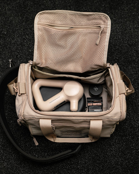 Inside top down view of Neutral beige KNKG mini CORE Duffel with theragun inside
