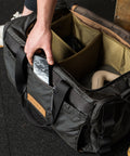 Person grabbing phone from front pocket of KNKG Waxed Canvas Duffel 