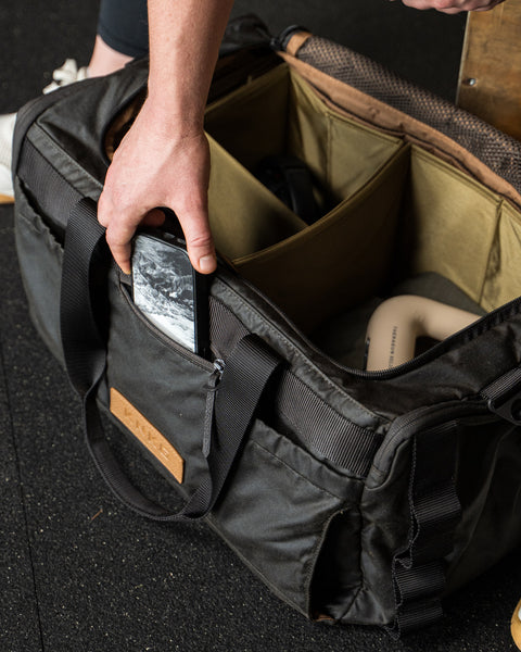 Person grabbing phone from front pocket of KNKG Waxed Canvas Duffel 