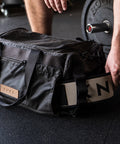 Close up of person pulling weightlifting belt out of KNKG Waxed Canvas Duffel 