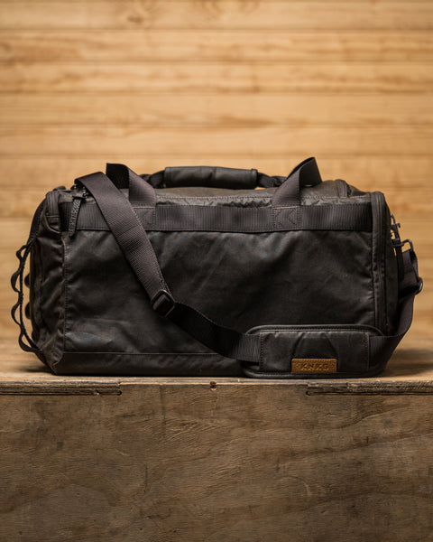 Back view of KNKG Waxed Canvas Duffel sitting on wooden box