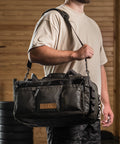 Athlete wearing KNKG Waxed Canvas Duffel over shoulder in barn style gym